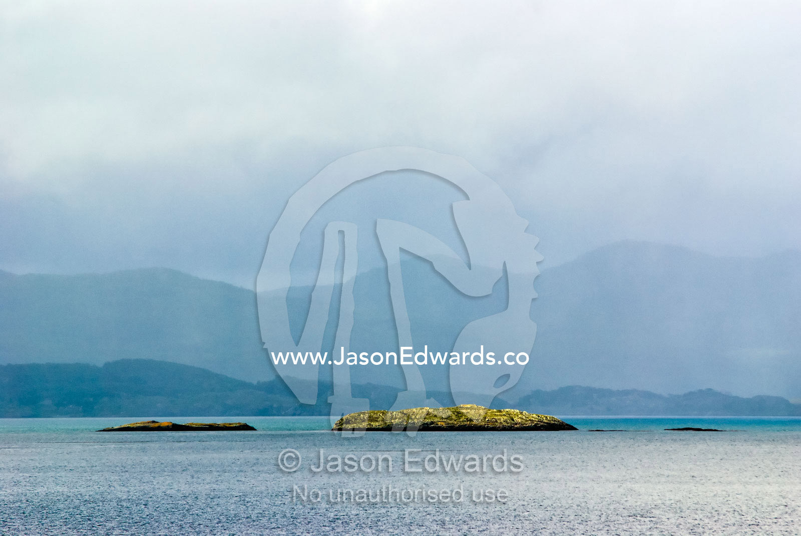 Small barren rocky islands are shipping hazards in a vast ocean bay. Ushuaia Bay, The Beagle Channel, Tierra del Fuego Archipelago, Straits of Magellan, Ushuaia, Tierra del Fuego Province, Patagonia, Argentina.