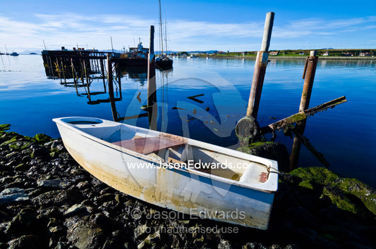 A small paddle boat beached on the rocky shore of a fishing village. The Beagle Channel, Tierra del Fuego Archipelago, Strait of Magellan, Tierra del Fuego Province, Patagonia, Argentina.