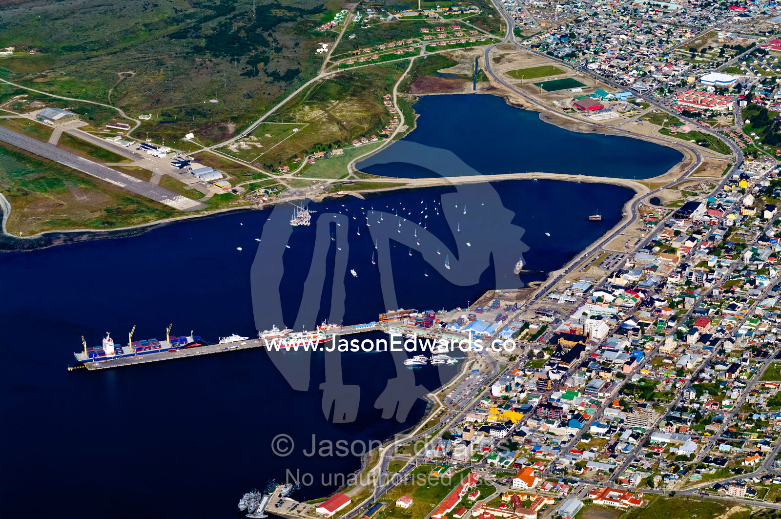 Container ships at wharf and yachts in a sheltered harbor by a city. Ushuaia Bay, The Beagle Channel, Tierra del Fuego Archipelago, Straits of Magellan, Ushuaia, Tierra del Fuego Province, Patagonia, Argentina.