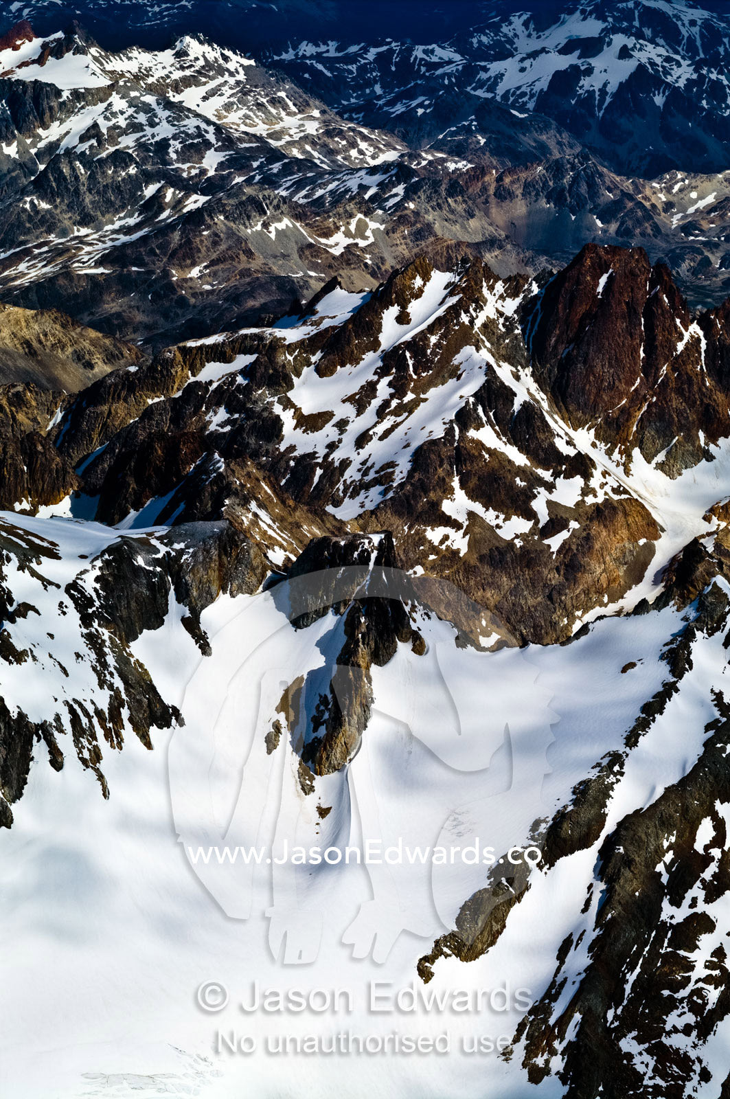 Dappled patches of cloud and sunlight on jagged snowy mountain peaks. Ushuaia, Martial Mountains, Fuegian Andes, Tierra del Fuego Archipelago, Straits of Magellan, Tierra del Fuego Province, Patagonia, Argentina.