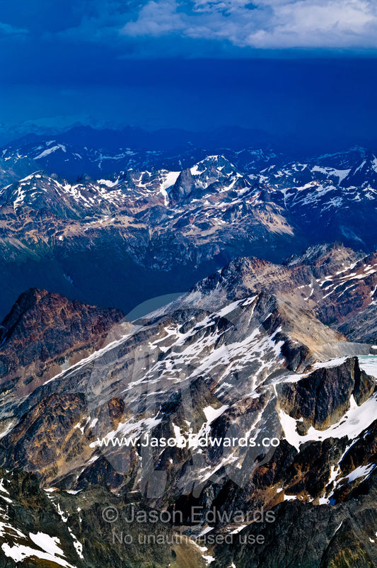 Dappled patches of cloud and sunlight on jagged snowy mountain peaks. Ushuaia, Martial Mountains, Fuegian Andes, Tierra del Fuego Archipelago, Straits of Magellan, Tierra del Fuego Province, Patagonia, Argentina.