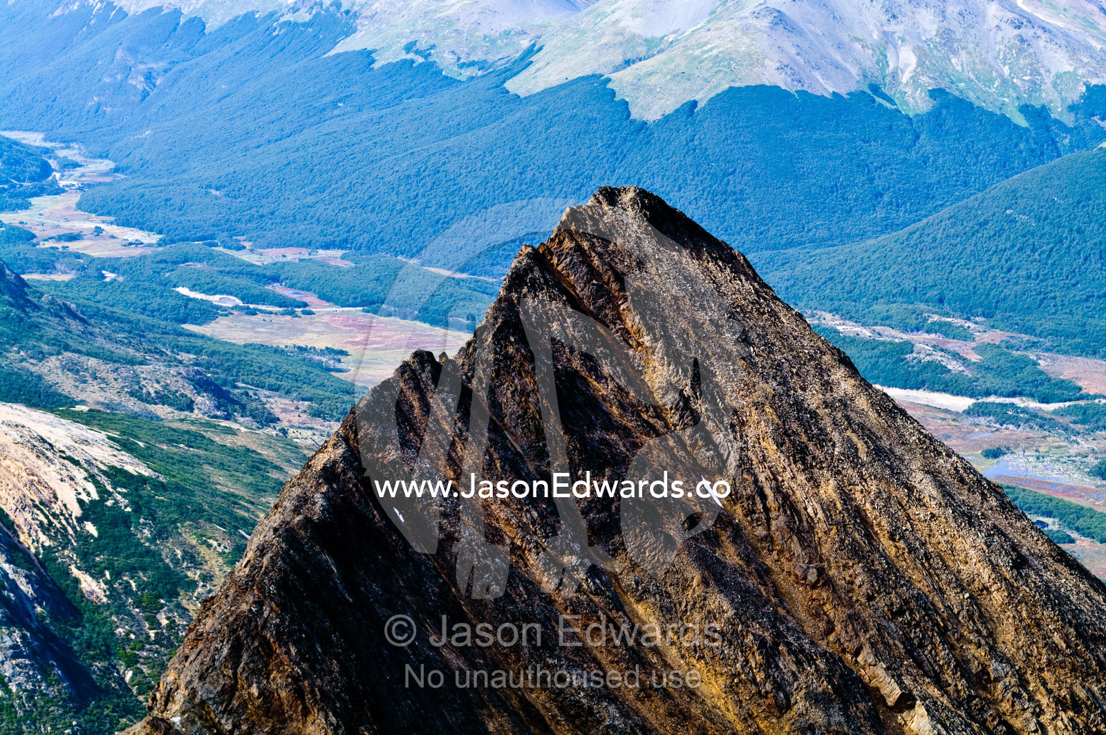 The jagged summit of a mountain overlooks a beech forest in a valley. Ushuaia, Martial Mountains, Fuegian Andes, Tierra del Fuego Archipelago, Straits of Magellan, Tierra del Fuego Province, Patagonia, Argentina.