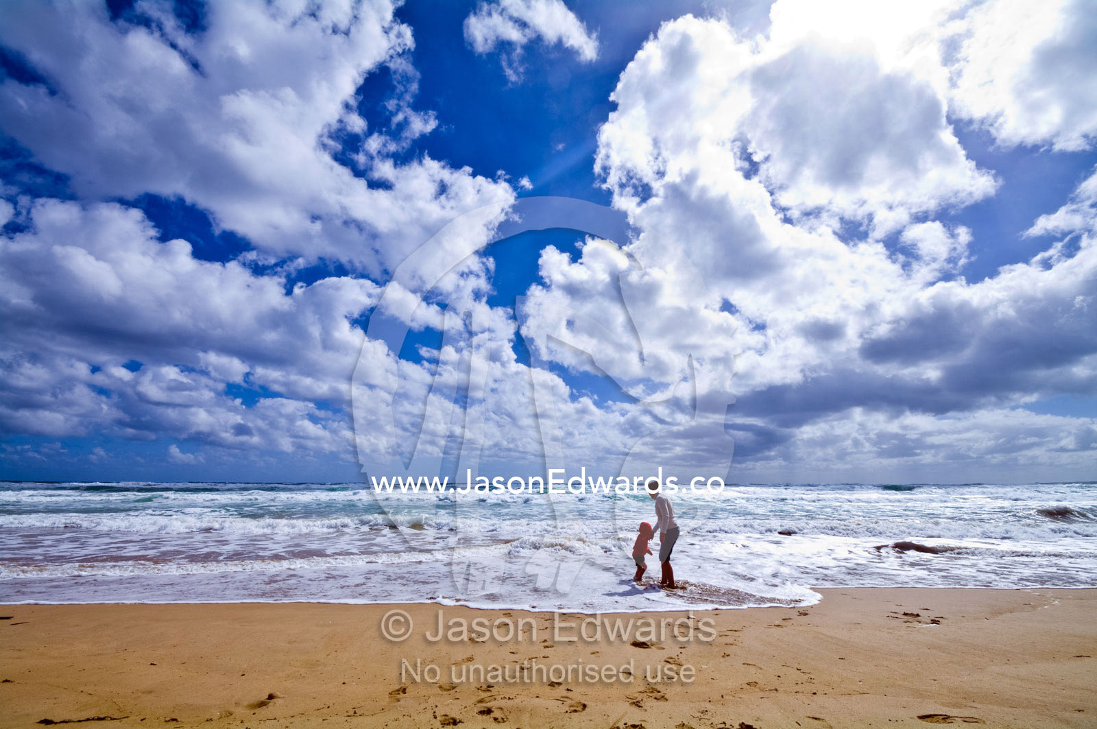 A mother and son play in the waves on a wide stormy beach in summer. Venus Bay, Cape Liptrap Coastal Park, Bass Strait, South Gippsland, Victoria, Australia.