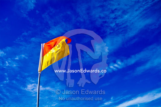 A surf life saving flag on a patrolled beach where it's safe to swim. Venus Bay, Cape Liptrap Coastal Park, Bass Strait, South Gippsland, Victoria, Australia.