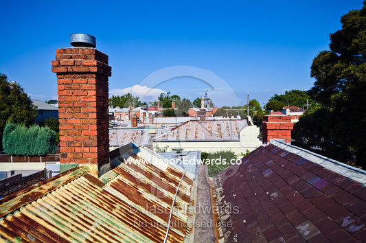 A Victorian red brick chimney pitched on a rusty corrugated iron roof. Carlton North, Melbourne, Victoria, Australia.