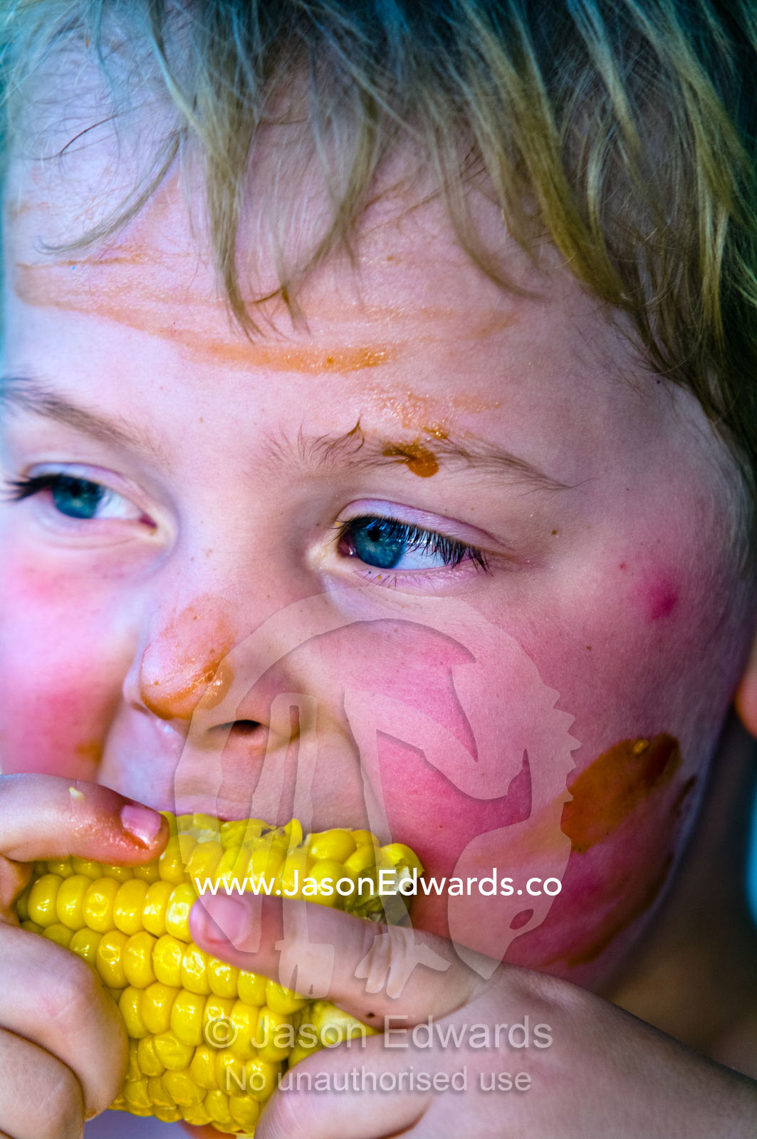A boy with tomato sauce on his face enjoying a fresh corn cob. Venus Bay, Cape Liptrap Coastal Park, Bass Strait, South Gippsland, Victoria, Australia.