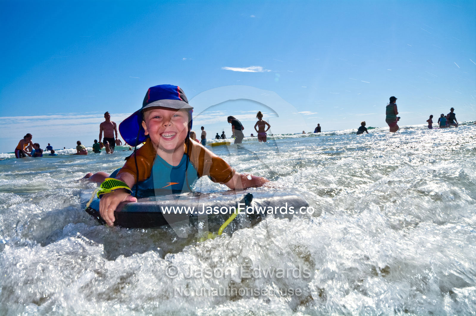 Laughing a young boy rides a body board in the waves at the beach. Venus Bay, Cape Liptrap Coastal Park, Bass Strait, South Gippsland, Victoria, Australia.