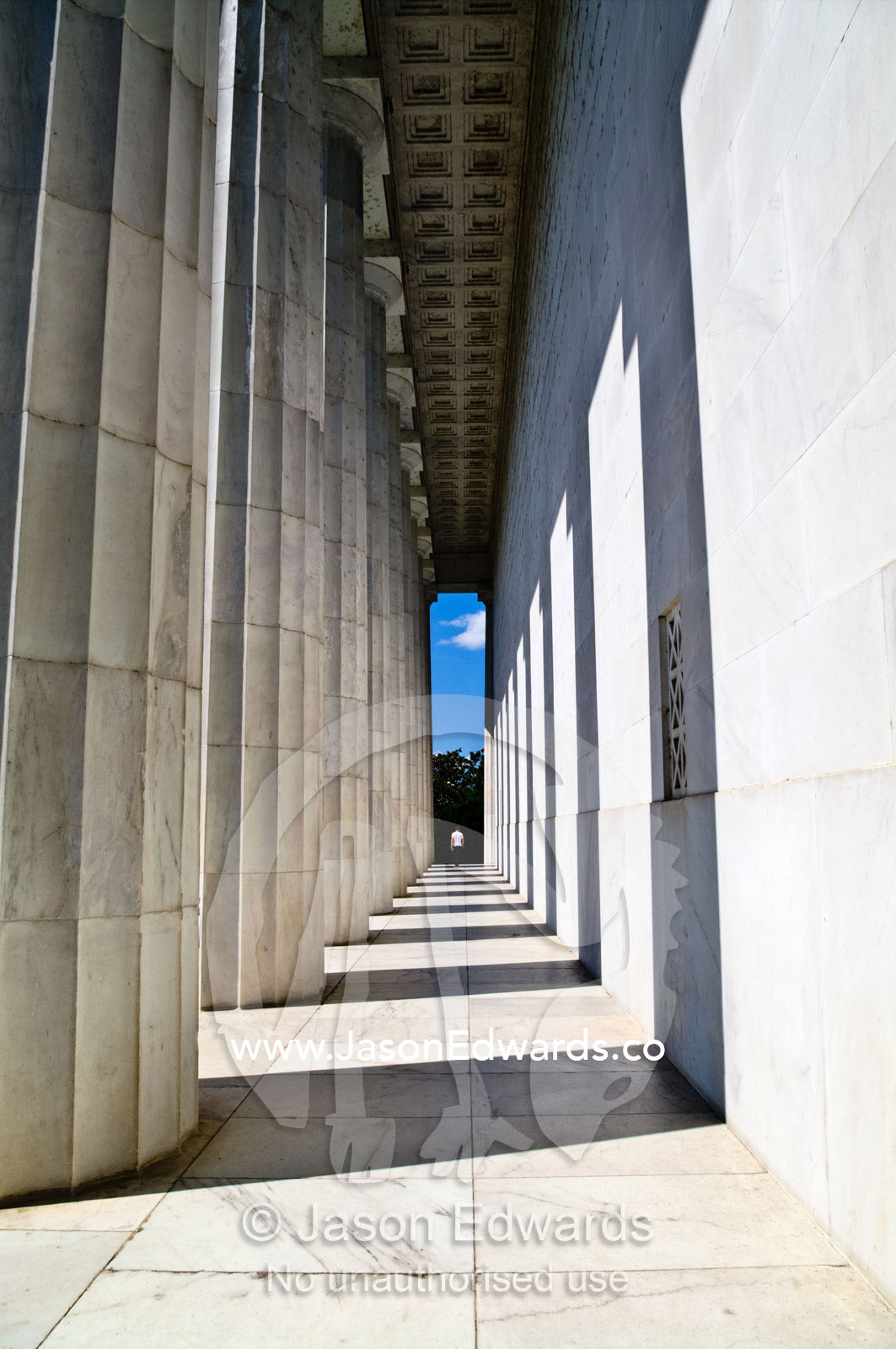 A tourist walks between marble Doric columns at the Lincoln Memorial. Lincoln Memorial, National Mall, Washington, District of Columbia, United States of America.