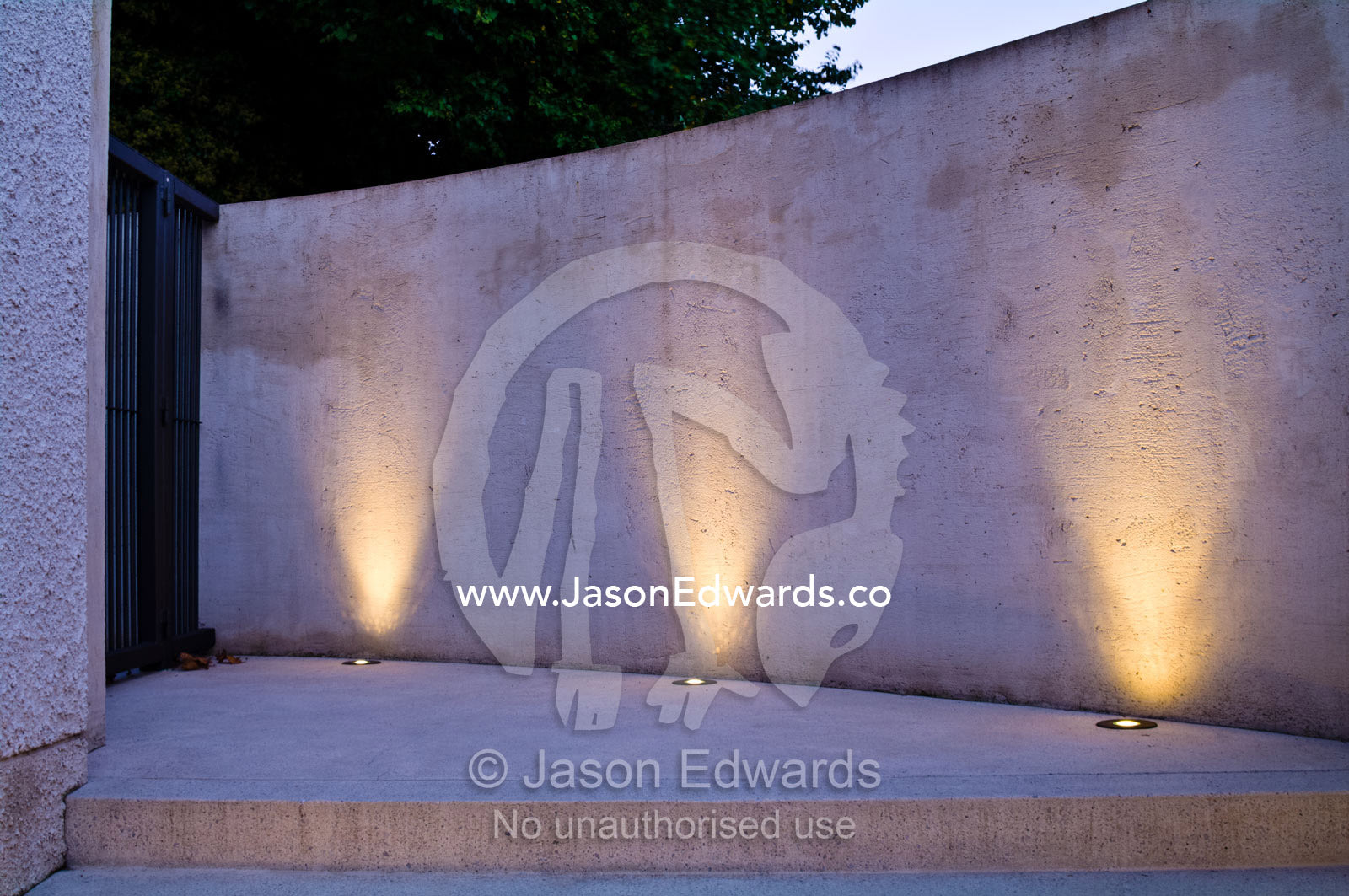 LED lighting in brass fixtures illuminate a concrete wall and step. Hawthorn, Melbourne, Victoria, Australia.