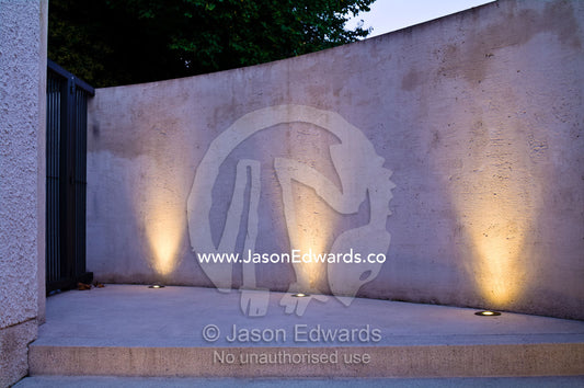 LED lighting in brass fixtures illuminate a concrete wall and step. Hawthorn, Melbourne, Victoria, Australia.