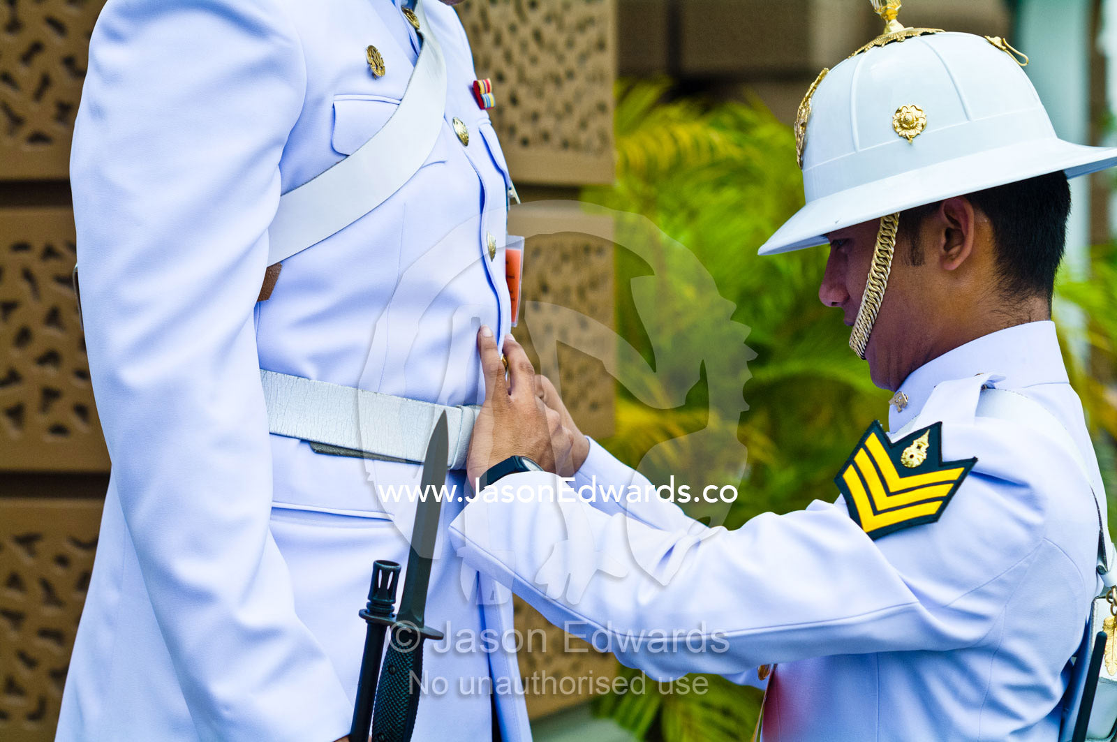 A soldier of the Kings Guard adjusts the belt and uniform of a guard. Chakri Maha Prasad, The Grand Palace, The Lord's Supreme Palace, Royal Palace, Bangkok, Thailand.