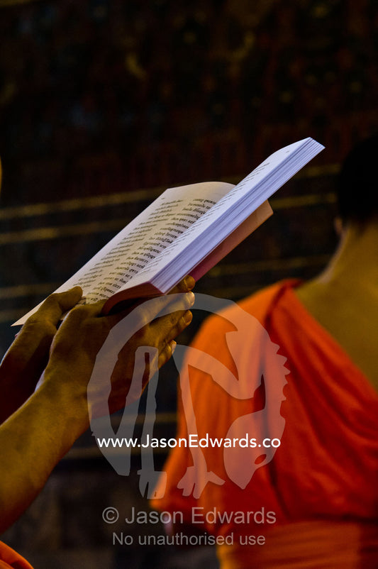 A Buddhist monk with a prayer book in the Ubosot, the temple's chapel. Wat Pho, Temple of the Reclining Buddha, Wat Chetuphon, Phra Nakhon District, Rattanakosin District, Bangkok, Thailand.