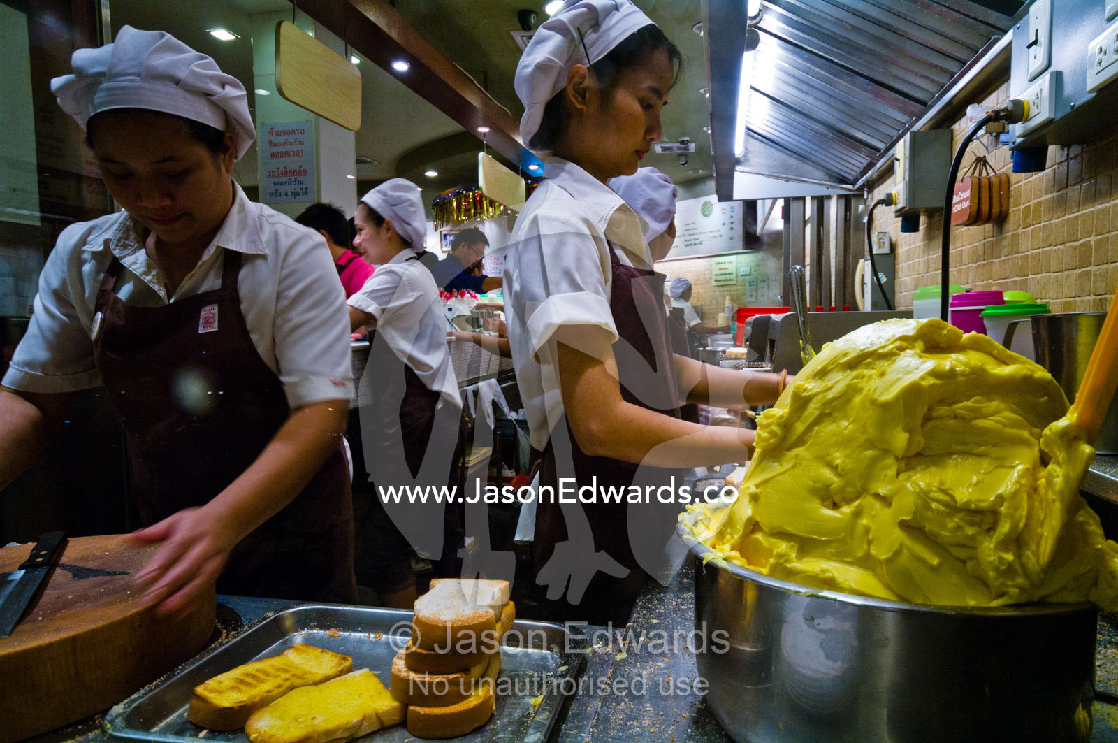 Staff butter thick slices of toast in a Bread and Milk Restaurant. Bangkok, Thailand.