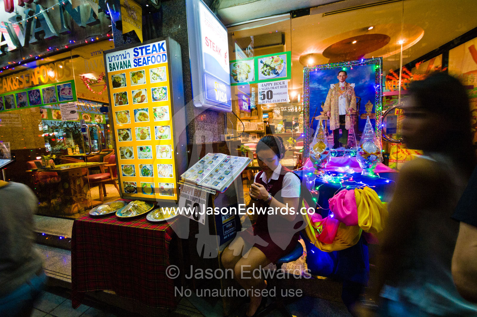 A busy street restaurant hostess texts a message on her mobile phone. MBK Centre, Mahboonkrong Shopping Center, Bangkok, Thailand.