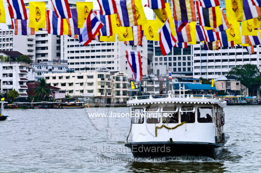 A commuter ferry transports passengers between piers along a river. Chao Phraya River, near the Grand Palace, The Lord's Supreme, Great Royal Palace, Bangkok, Thailand.