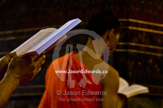 A Buddhist monk with a prayer book in the Ubosot, the temple's chapel. Wat Pho, Temple of the Reclining Buddha, Wat Chetuphon, Phra Nakhon District, Rattanakosin District, Bangkok, Thailand.