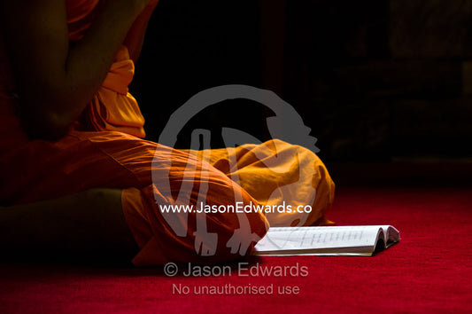 A Buddhist monk with a prayer book in the Ubosot, the temple's chapel. Wat Pho, Temple of the Reclining Buddha, Wat Chetuphon, Phra Nakhon District, Rattanakosin District, Bangkok, Thailand.