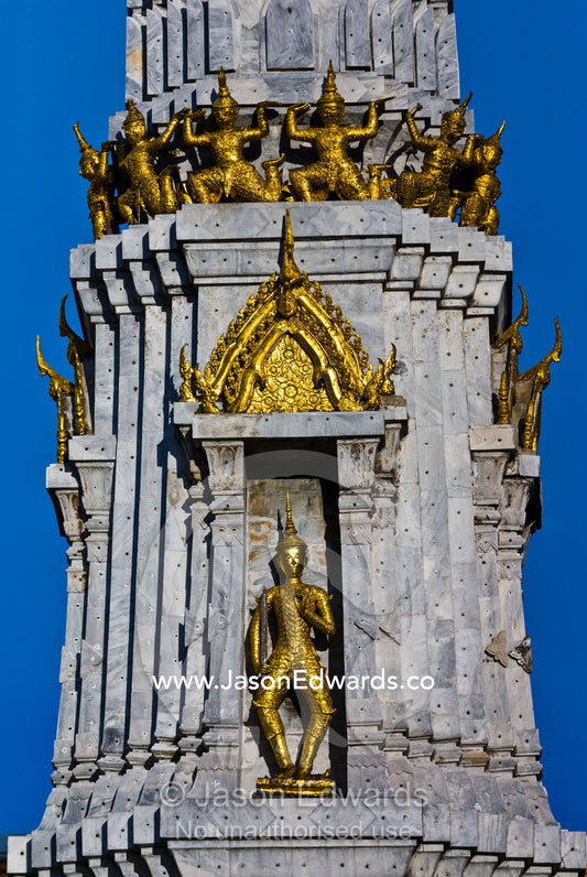 Golden statues of Garuda circle a prang above a statue of the Buddha. Wat Pho, Temple of the Reclining Buddha, Wat Chetuphon, Phra Nakhon District, Rattanakosin District, Bangkok, Thailand.