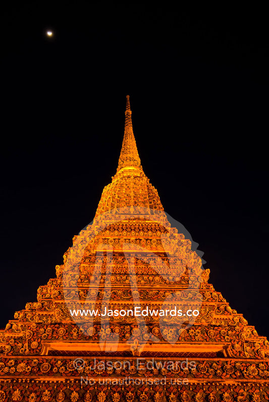 Moonrise over the prang of the Phra Maha Chedi rising into night sky. Wat Pho, Phra Maha Chedi, Bangkok, Thailand.