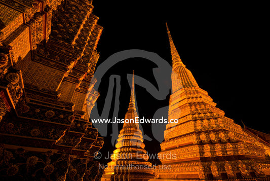 Floodlights on the prang of the Phra Maha Chedi rising into night sky. Wat Pho, Phra Maha Chedi, Bangkok, Thailand.