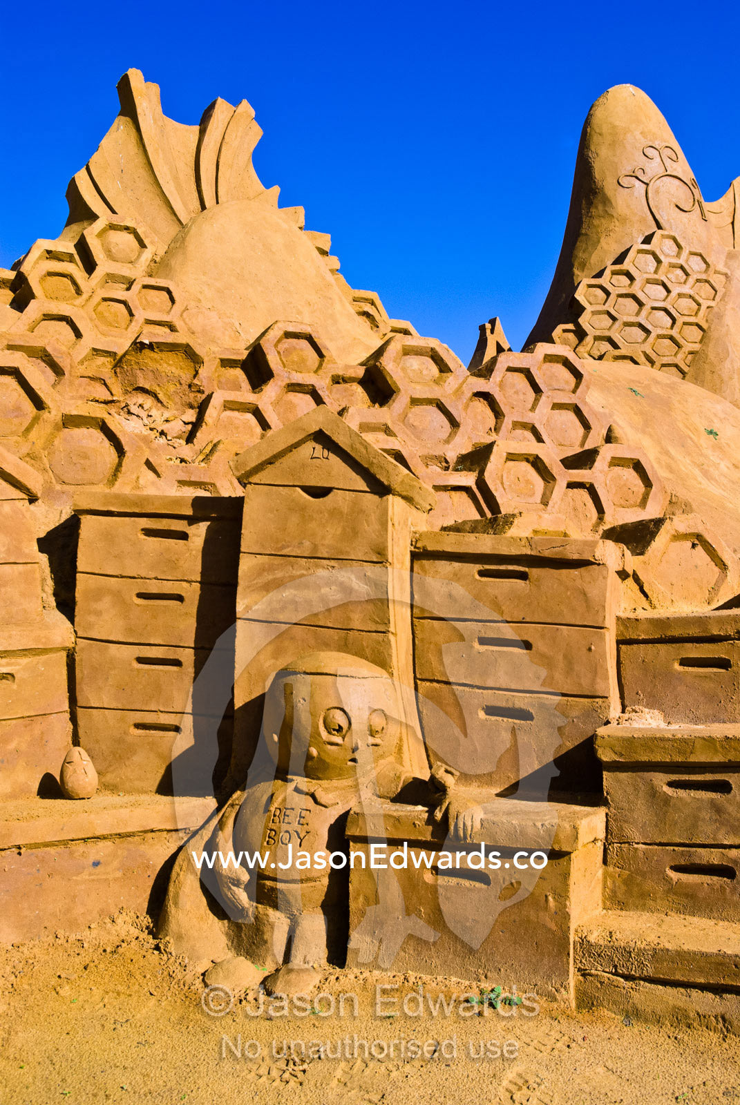 A professional sand sculpture features bee hive boxes and honeycomb. Frankston, Port Phillip Bay, Melbourne, Victoria, Australia.