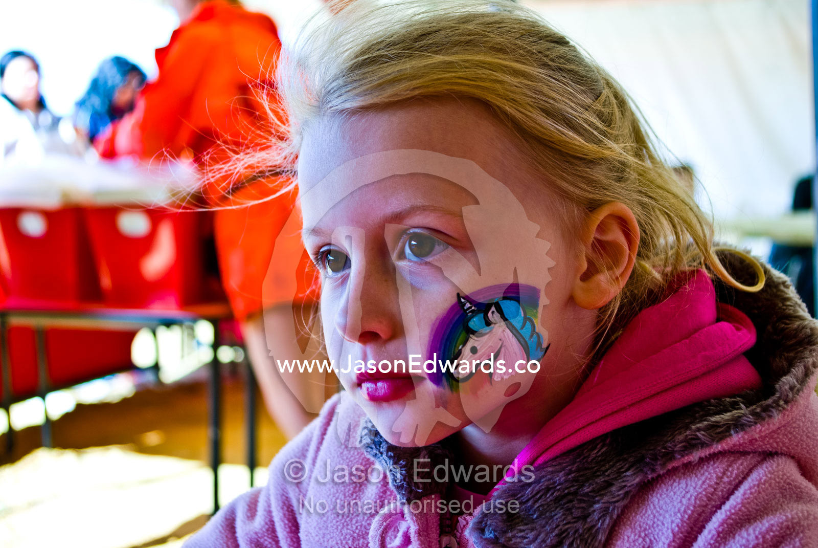A blonde girl with a unicorn and rainbow painted on her cheek. Frankston, Port Phillip Bay, Melbourne, Victoria, Australia.