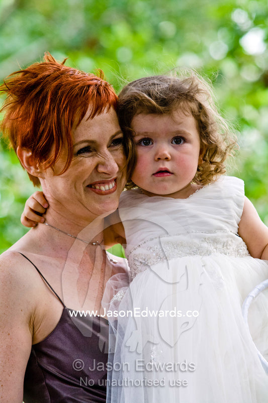 A flower girl rests with her bridesmaid mother at a garden wedding. Park Orchards, Melbourne, Victoria, Australia.
