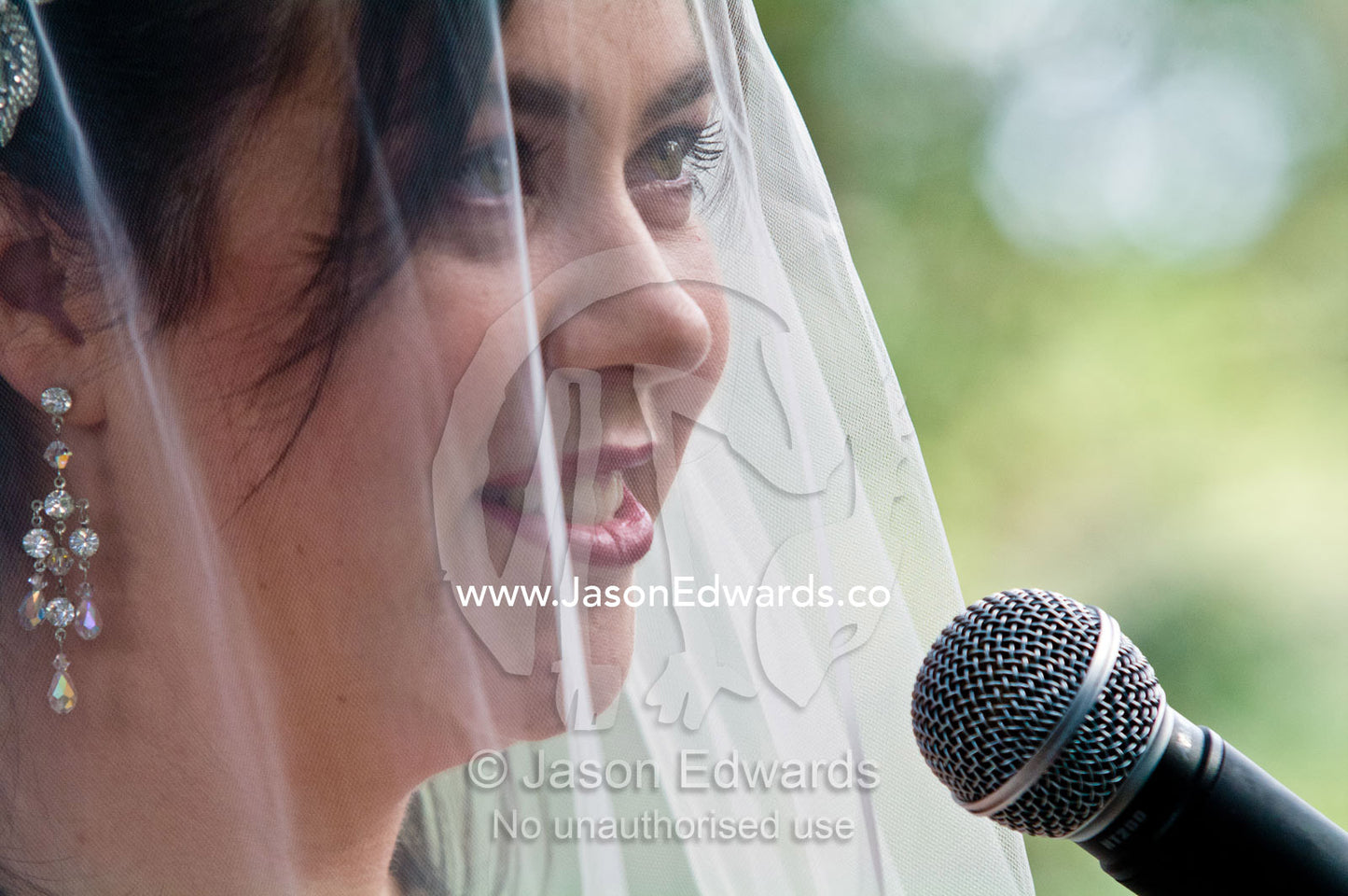 A bride speaks her wedding vows into a microphone at a garden wedding. Park Orchards, Melbourne, Victoria, Australia.