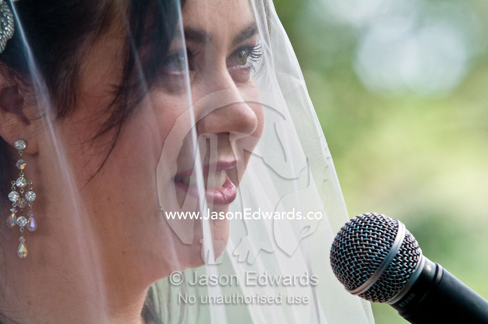 A bride speaks her wedding vows into a microphone at a garden wedding. Park Orchards, Melbourne, Victoria, Australia.