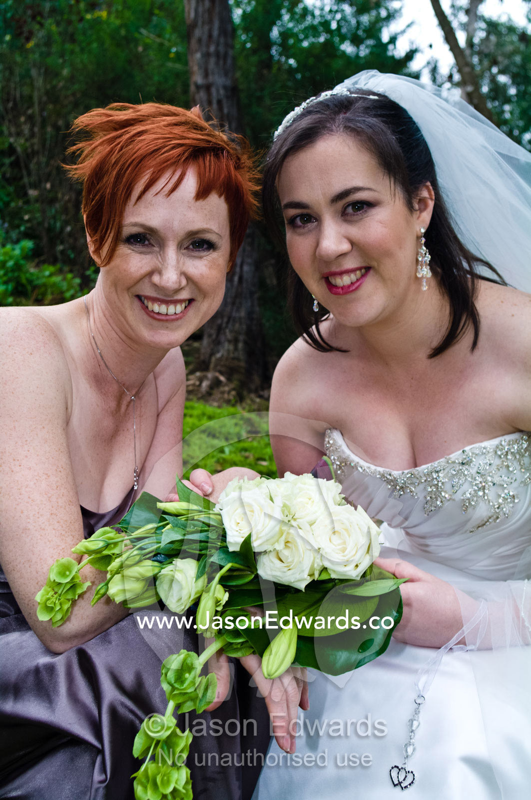 A bride with her bouquet and bridesmaid on her wedding day. Park Orchards, Melbourne, Victoria, Australia.