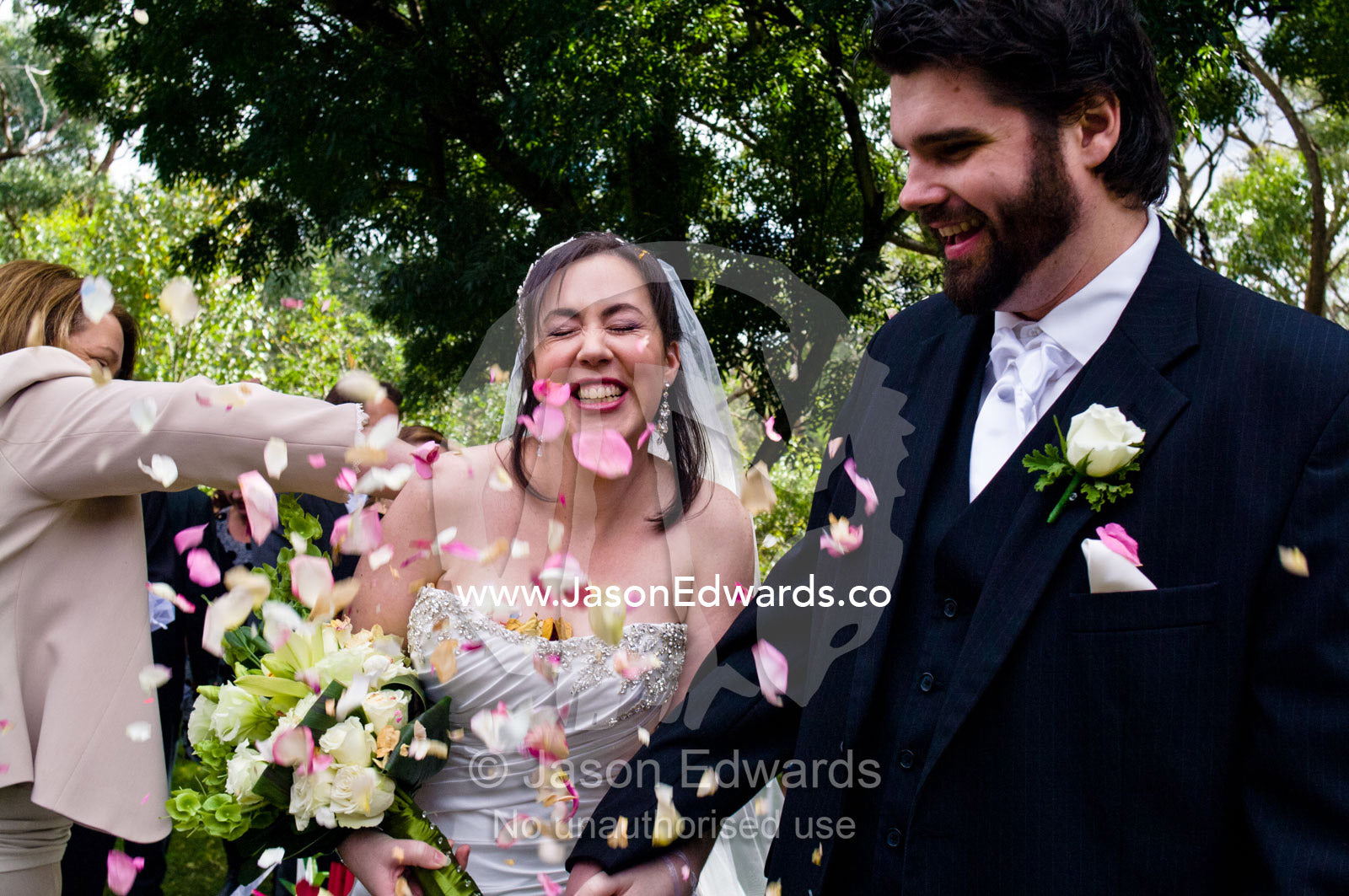 A laughing bride showered in dried rose petal potpourri confetti. Park Orchards, Melbourne, Victoria, Australia.