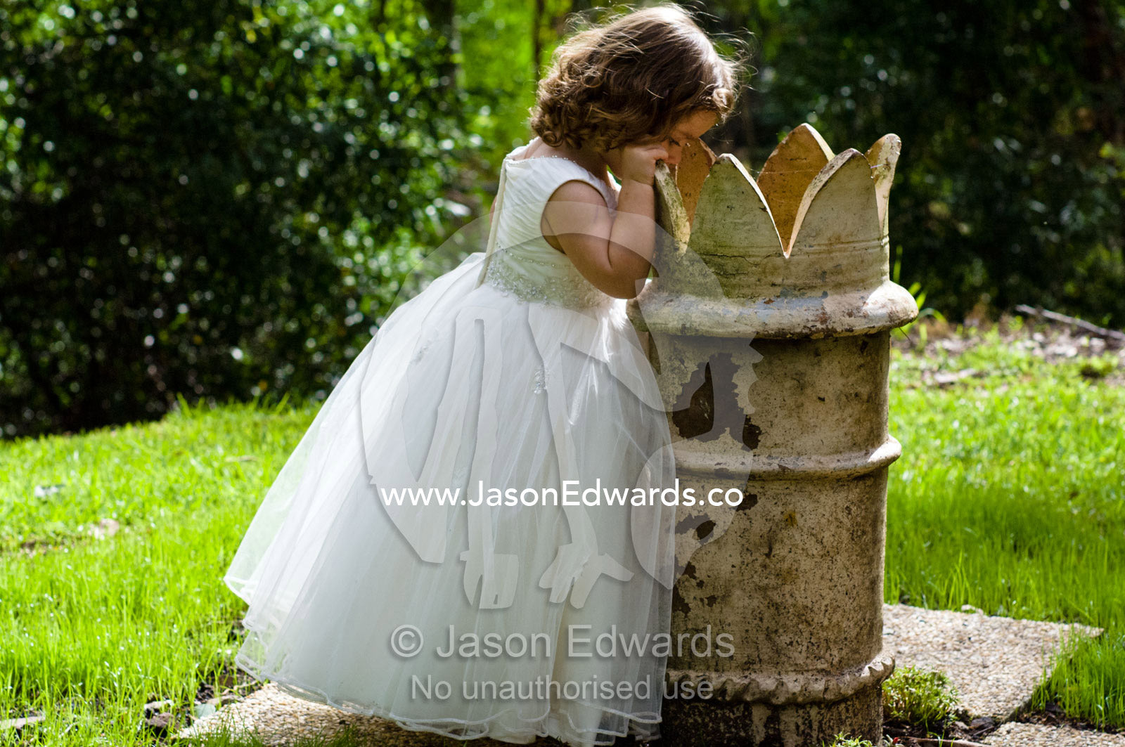 Inquisitive flower girl peers inside a sculpture at a garden wedding. Park Orchards, Melbourne, Victoria, Australia.