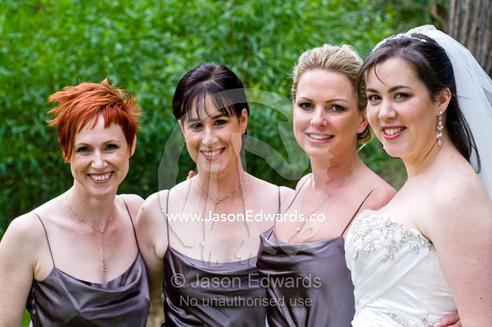 A bride with her bridesmaids in a garden on her wedding day. Park Orchards, Melbourne, Victoria, Australia.