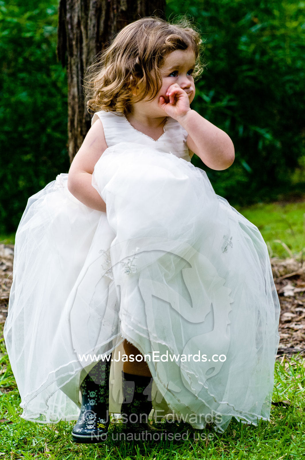 A flower girl lifts her dress up whilst walking at a garden wedding. Park Orchards, Melbourne, Victoria, Australia.