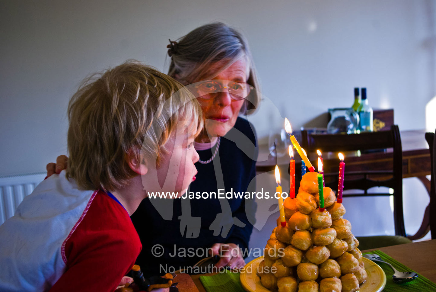 A grandmother and grandson blow out candles on a croquembouche cake. Malvern East, Melbourne, Victoria, Australia.