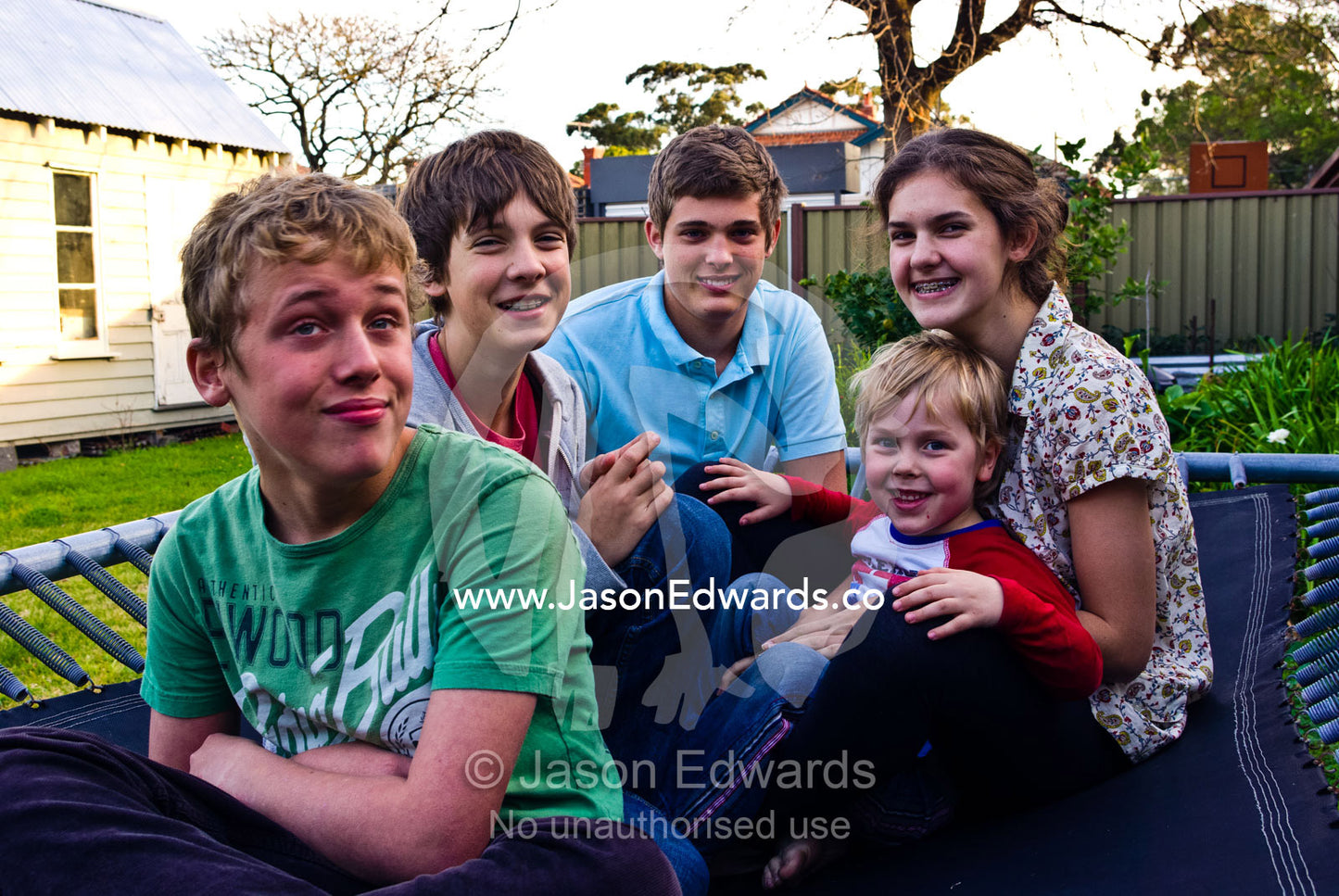 Cousins playing happily together on a backyard trampoline. Malvern East, Melbourne, Victoria, Australia.