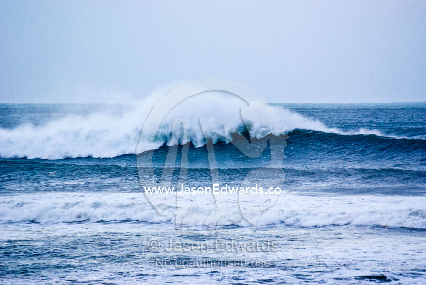 Huge foaming surf rolls in over a reef break during a winter swell. Point Danger, Torquay, Surf Coast, Victoria, Australia.