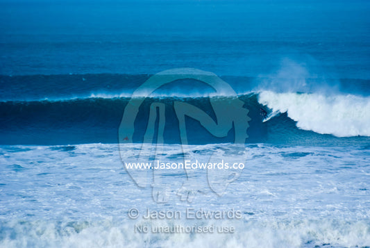 A lone surfer braves huge waves during a winter swell at Bells Beach. Bells Beach Surfing Recreation Reserve, Surf Coast, Victoria, Australia.