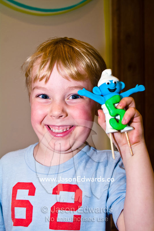 A happy birthday boy displays the Smurf from his fifth birthday cake. North Carlton, Melbourne, Victoria, Australia.