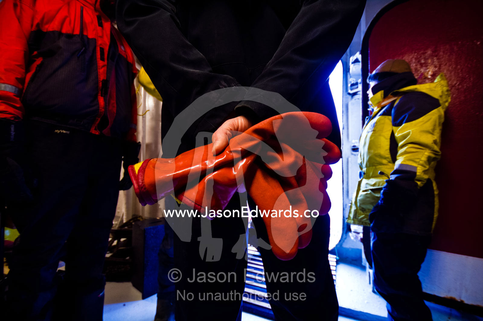 An Antarctic expedition leader with rubber gloves waits by a hull door. Prospect Point, Crystal Sound, Antarctic Peninsula, Antarctic Circle, Antarctica.