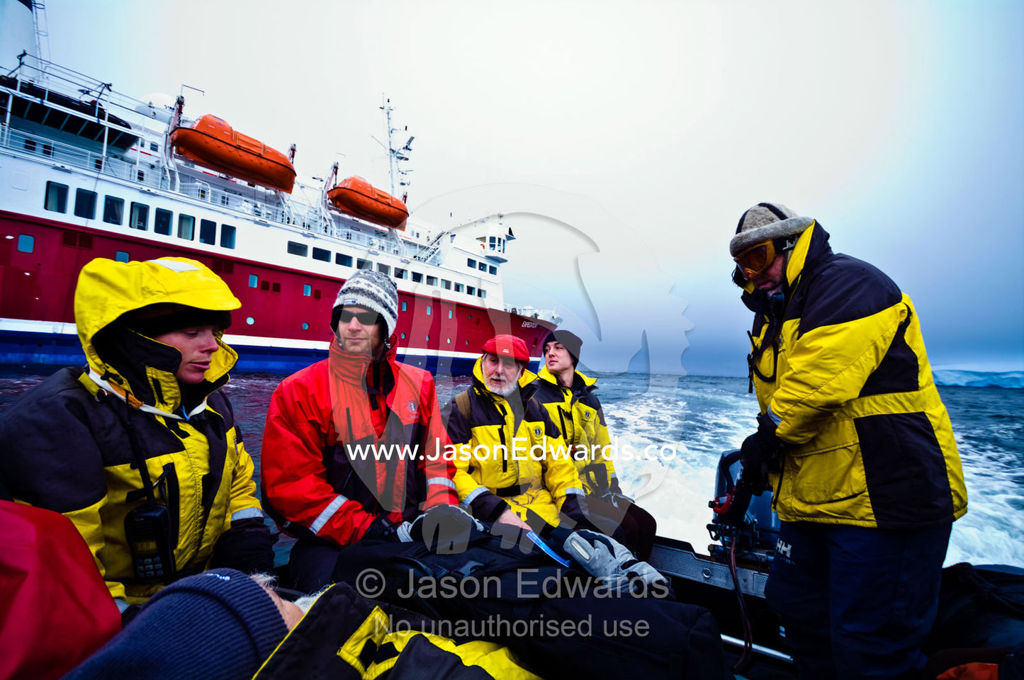 An Antarctic expedition crew in waterproof jackets in a zodiac boat. Prospect Point, Crystal Sound, Antarctic Peninsula, Antarctic Circle, Antarctica.