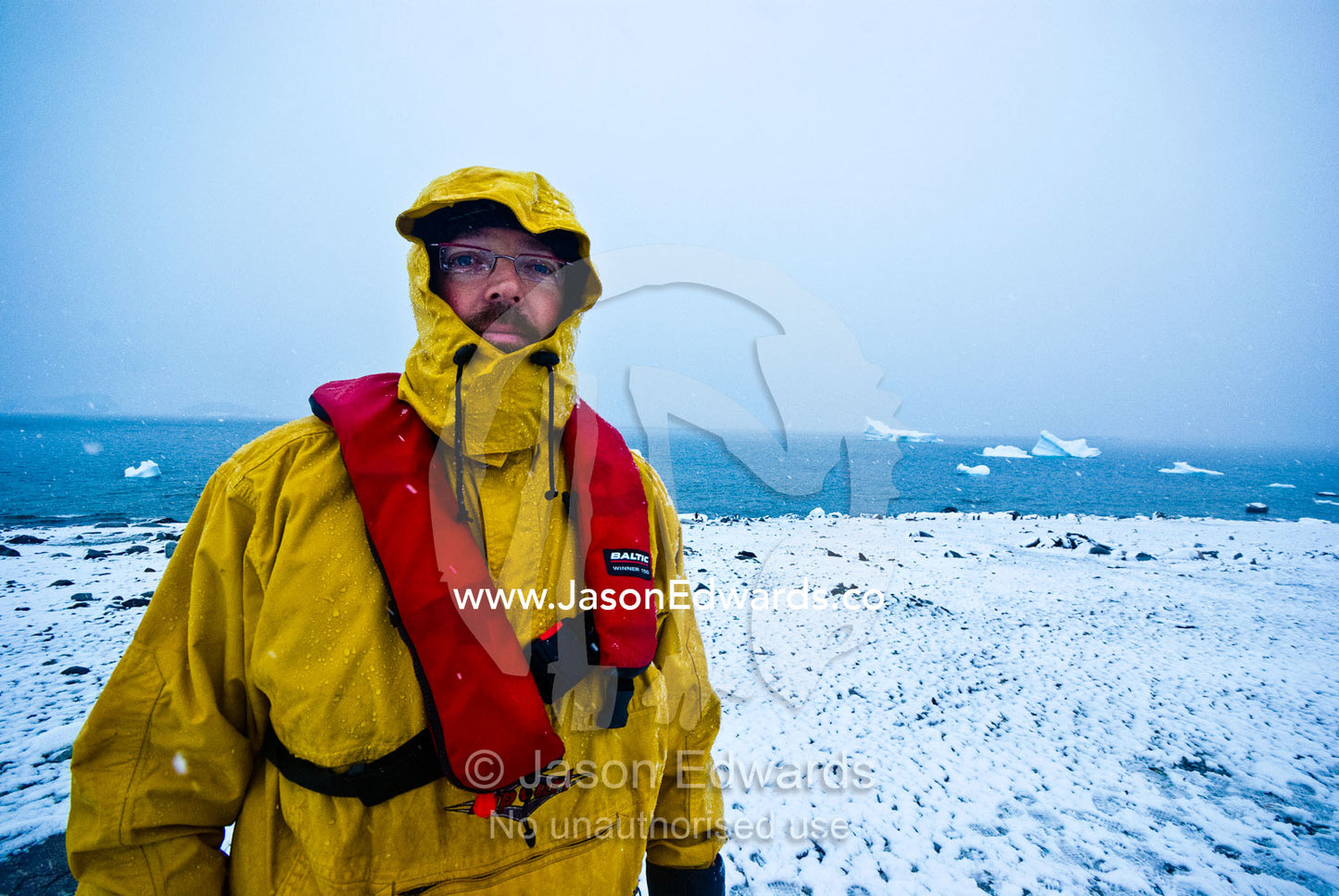 A tourist amidst snow and icebergs on a rugged and bleak island. Danco Island, Antarctic Peninsula, Antarctica.