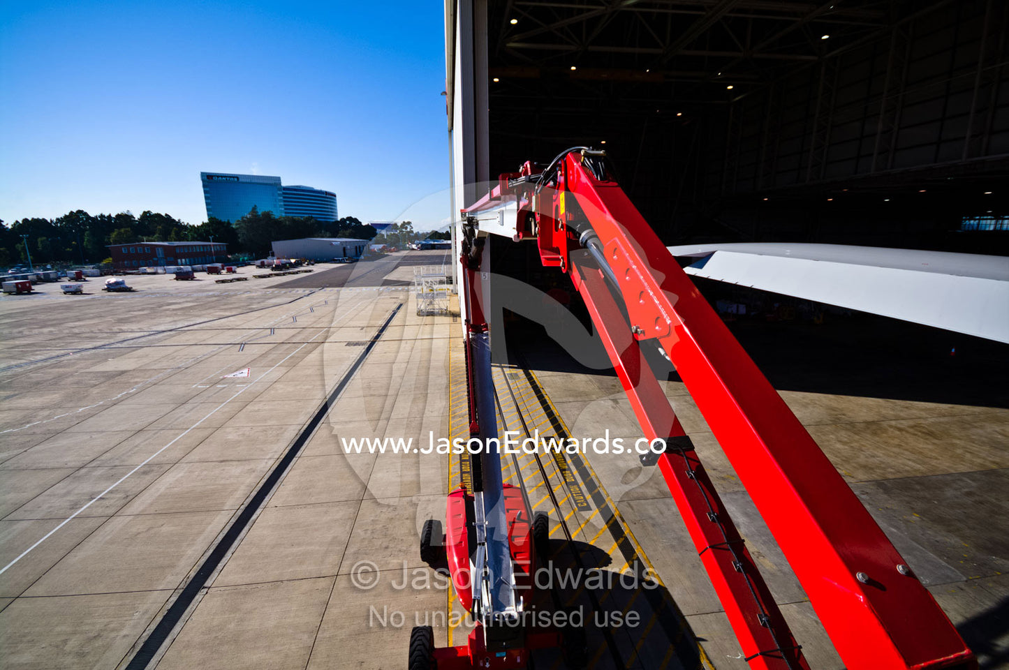 The arm of a high-lift crane extended into an aircraft hanger door. Kingsford Smith Airport, Mascot, Sydney, New South Wales, Australia.
