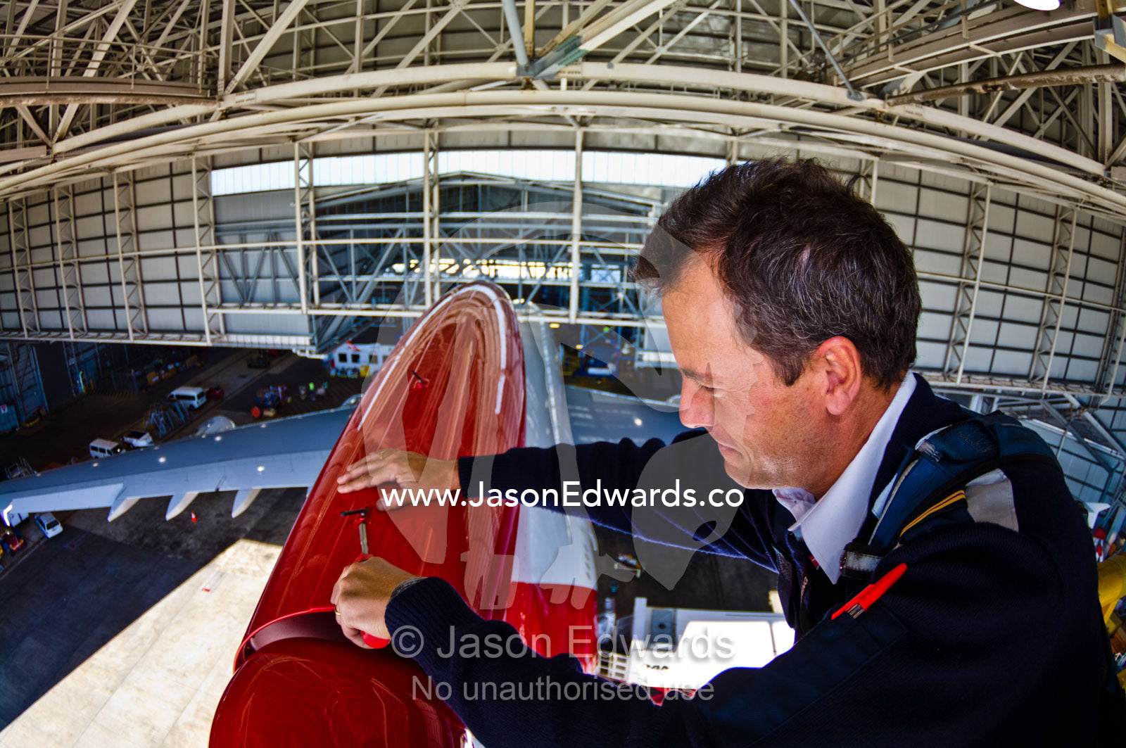 An aeronautical engineer doing maintenance repairs to a jet airliner. Kingsford Smith Airport, Mascot, Sydney, New South Wales, Australia.