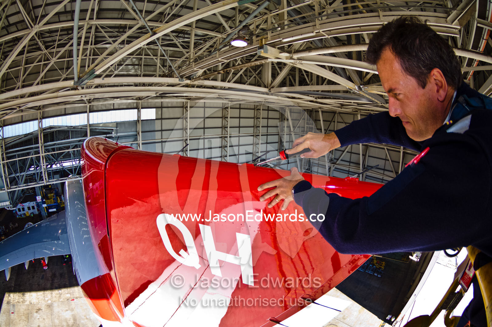 An aeronautical engineer doing maintenance repairs to a jet airliner. Kingsford Smith Airport, Mascot, Sydney, New South Wales, Australia.