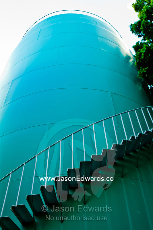 Stairs spiral around the wall of a turquoise airport deluge water tank. Kingsford Smith Airport, Mascot, Sydney, New South Wales, Australia.