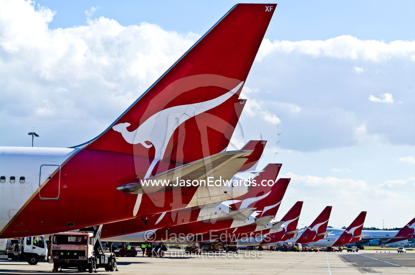 A row of jet airplanes parked at a terminal to collect passengers. Kingsford Smith Airport, Mascot, Sydney, New South Wales, Australia.