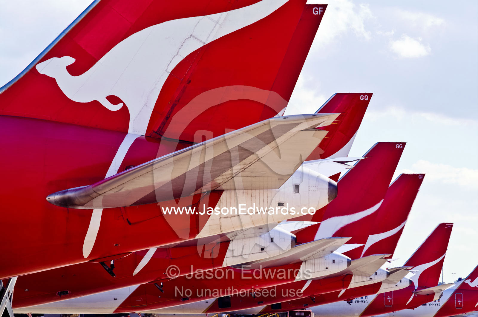 A row of jet airplanes parked at a terminal to collect passengers. Kingsford Smith Airport, Mascot, Sydney, New South Wales, Australia.