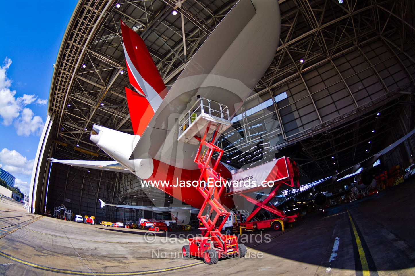 An aeronautical engineer repairs a jet airliner wing from a crane. Kingsford Smith Airport, Mascot, Sydney, New South Wales, Australia.
