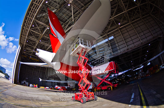 An aeronautical engineer repairs a jet airliner wing from a crane. Kingsford Smith Airport, Mascot, Sydney, New South Wales, Australia.